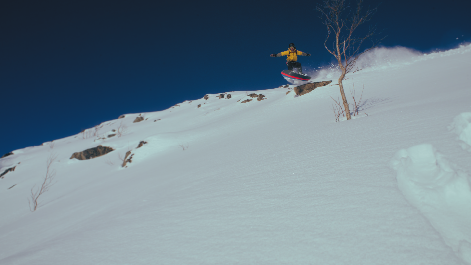Snowboarder dropping a cliff in fresh powder