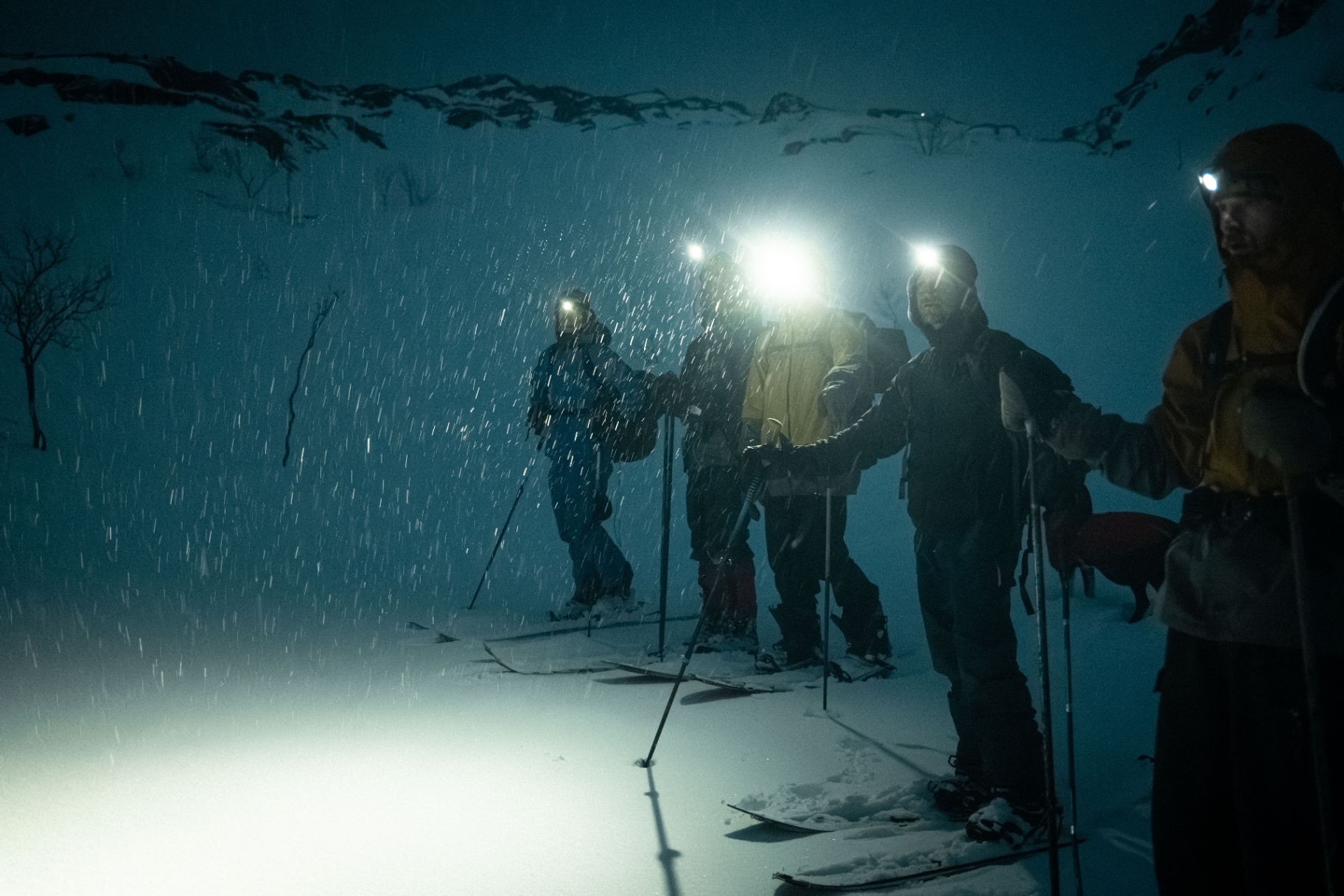 Group of ski-tourers in falling snow at night
